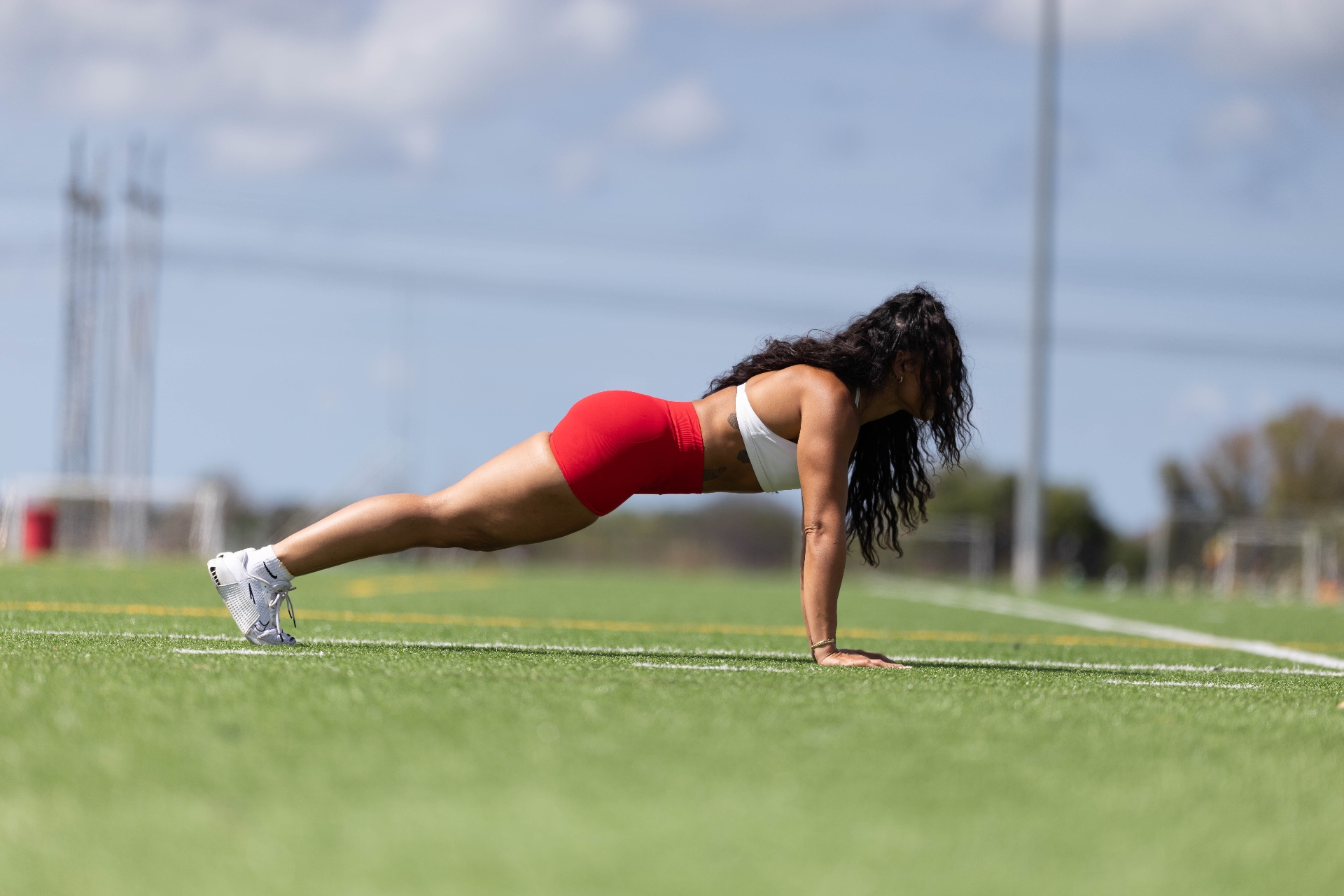 LabellaBeast founder holding a straight arm plank on a turf field