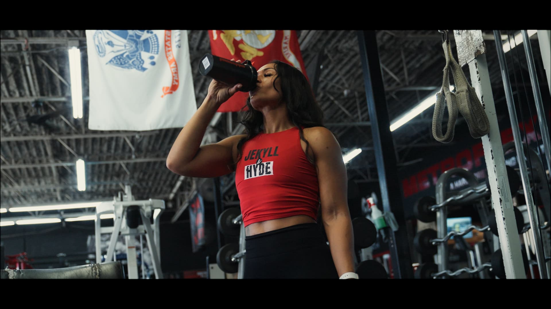 Shamaira taking a drink between sets under the gym flags